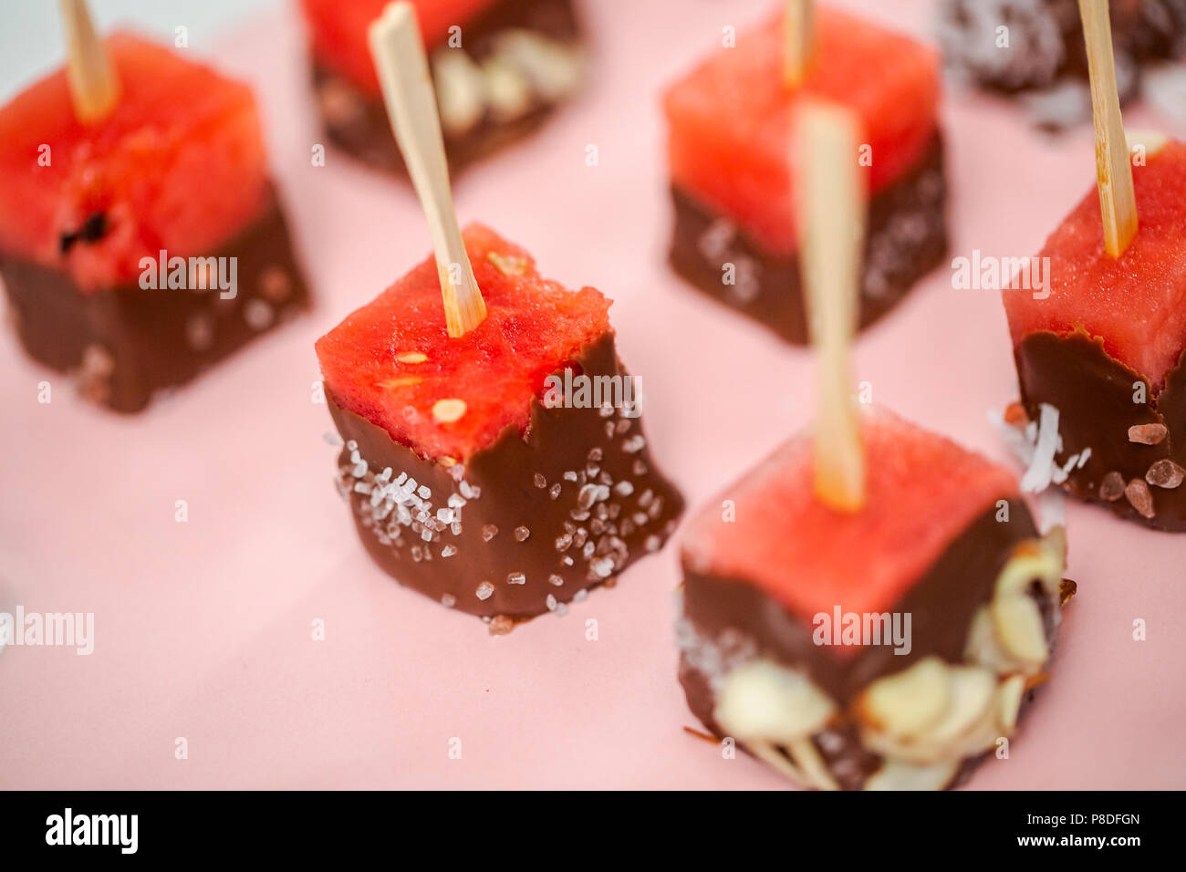 Preparing watermelon appetizers dipped in chocolate and sprinked with
