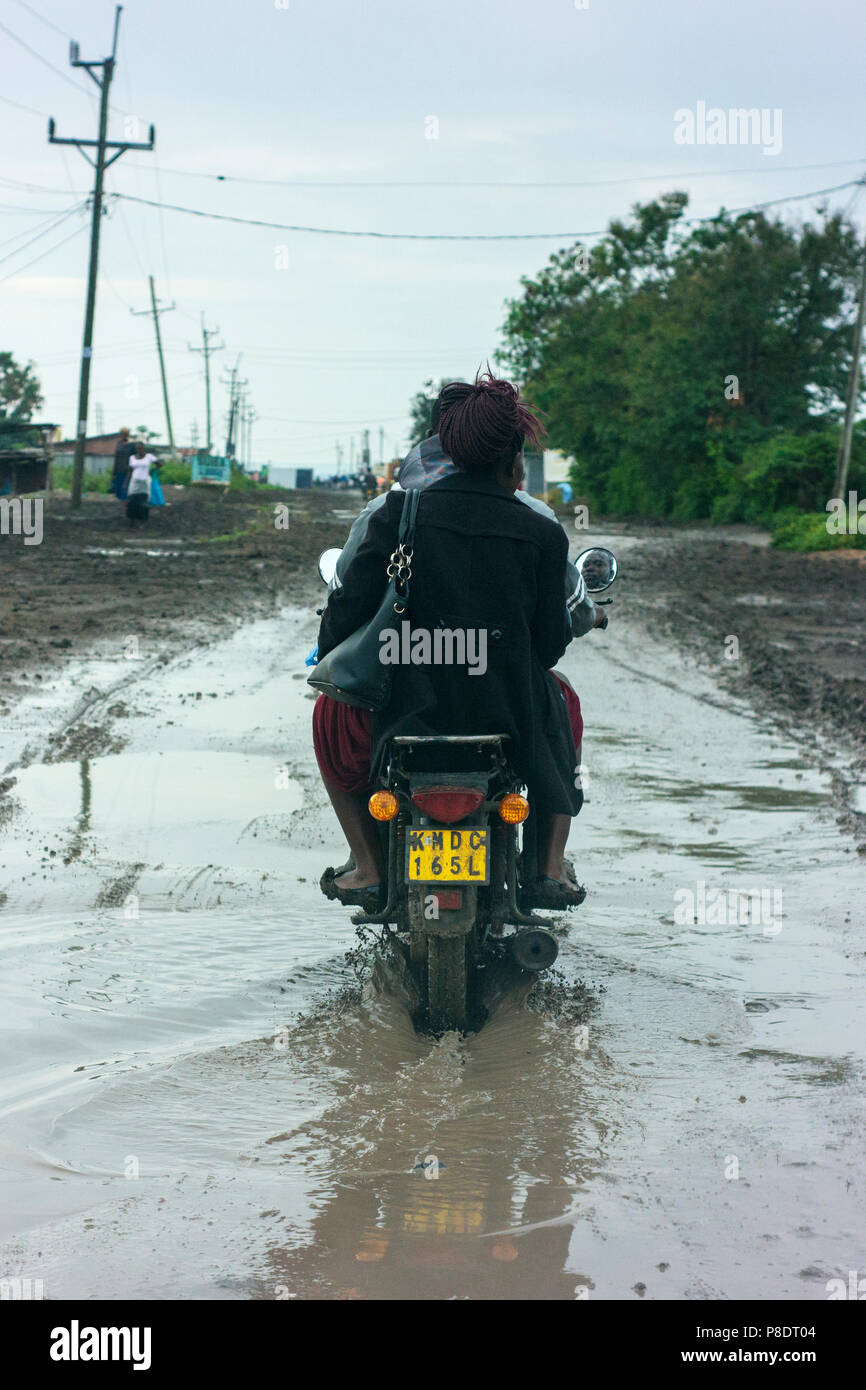 A motorcycle makes its way through floodwaters on a road on the outskirts of Sori, in rural Kenya. Stock Photo