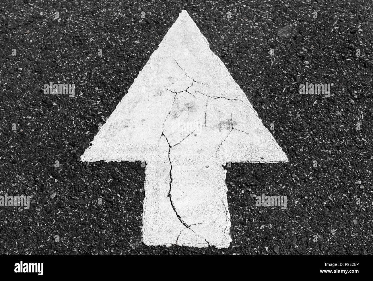 White arrow over dark asphalt, straight drive direction, close-up photo Stock Photo