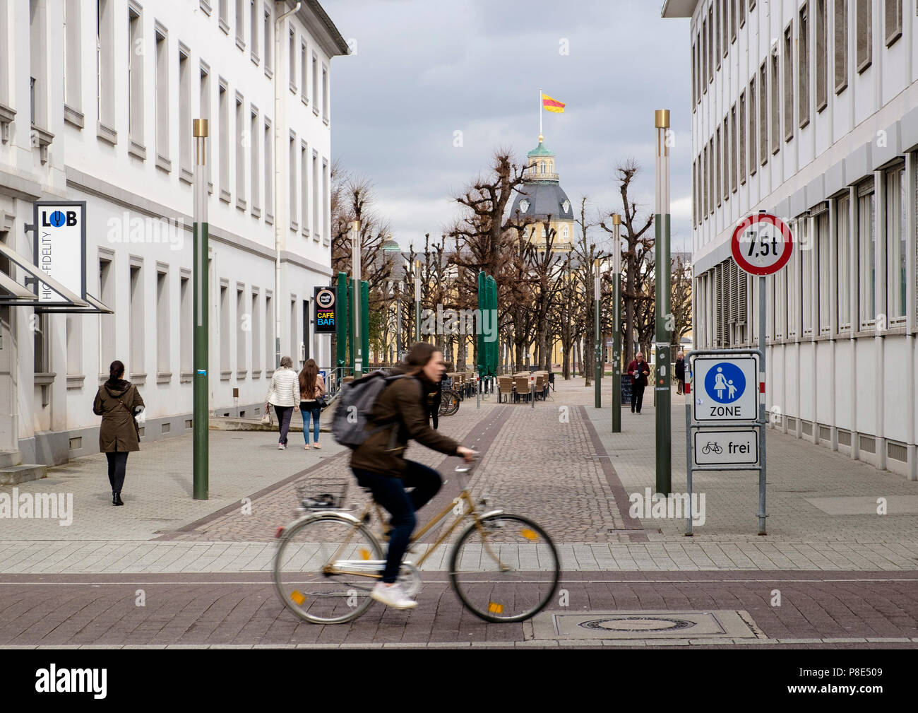 Woman cycling in the city centre of Karlsruhe with Karlsruhe Palace, Schloss Karlsruhe, in the background, Baden-Württemberg, Germany Stock Photo