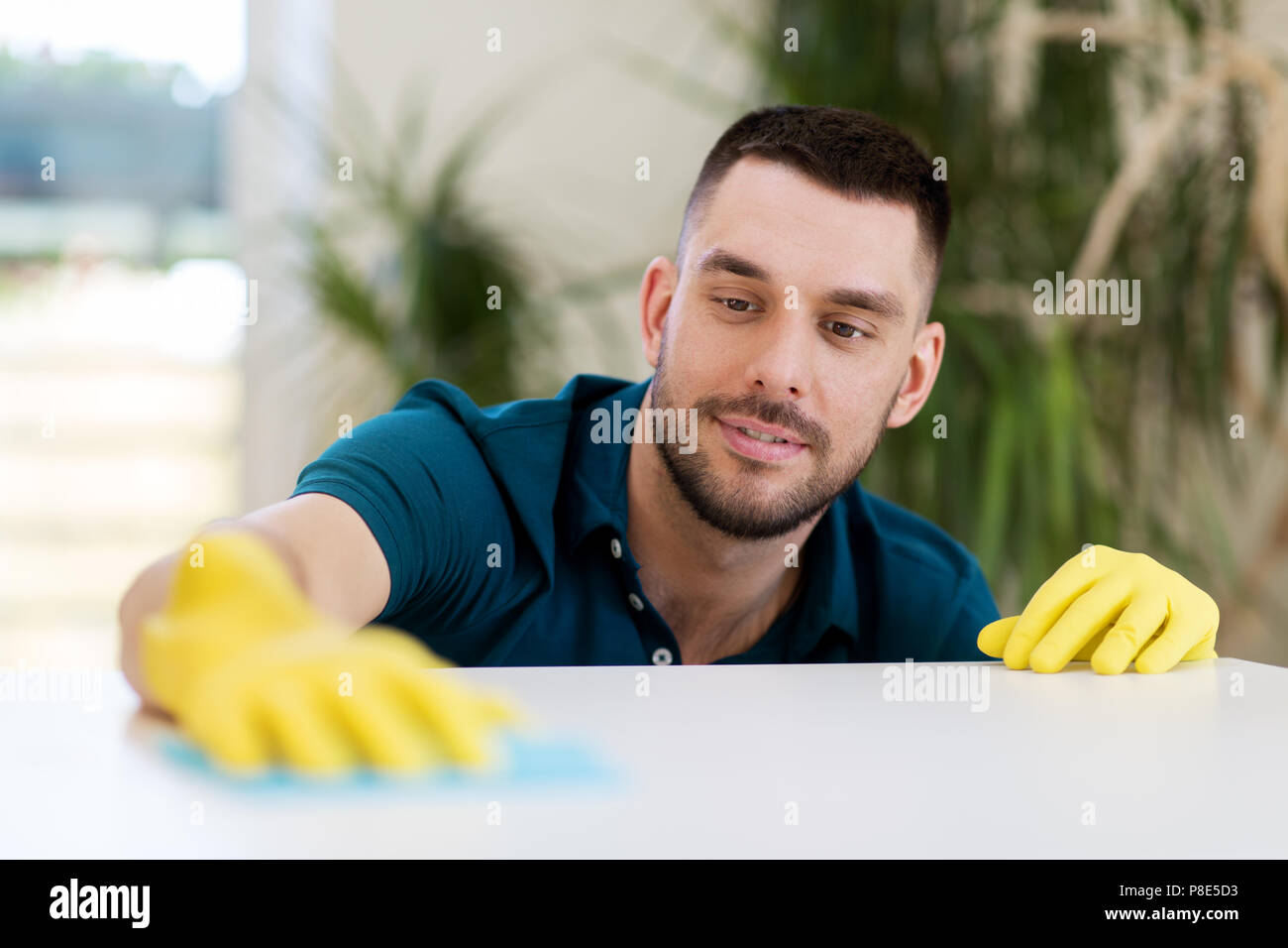 man cleaning table with cloth at home Stock Photo