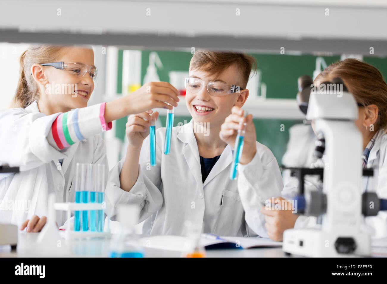 Изучение химии в школе. Ребенок в пробирке. Урок химии. Дети изучают химию в школе. Школьник с пробирками.