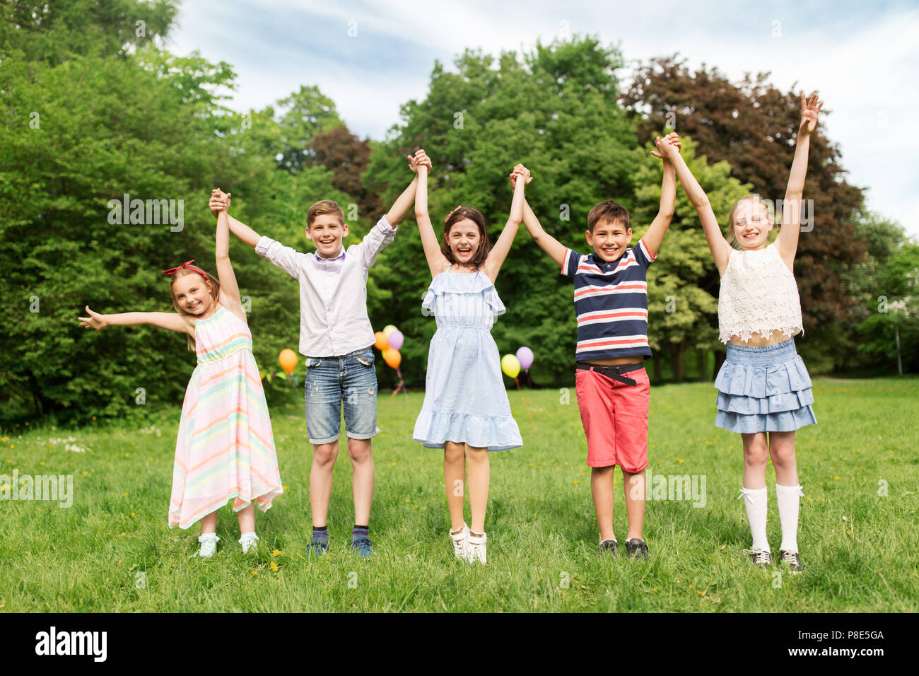 happy kids holding hands in summer park Stock Photo - Alamy