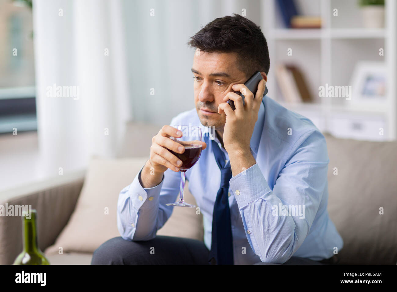 drunk man with alcohol calling on smartphone Stock Photo