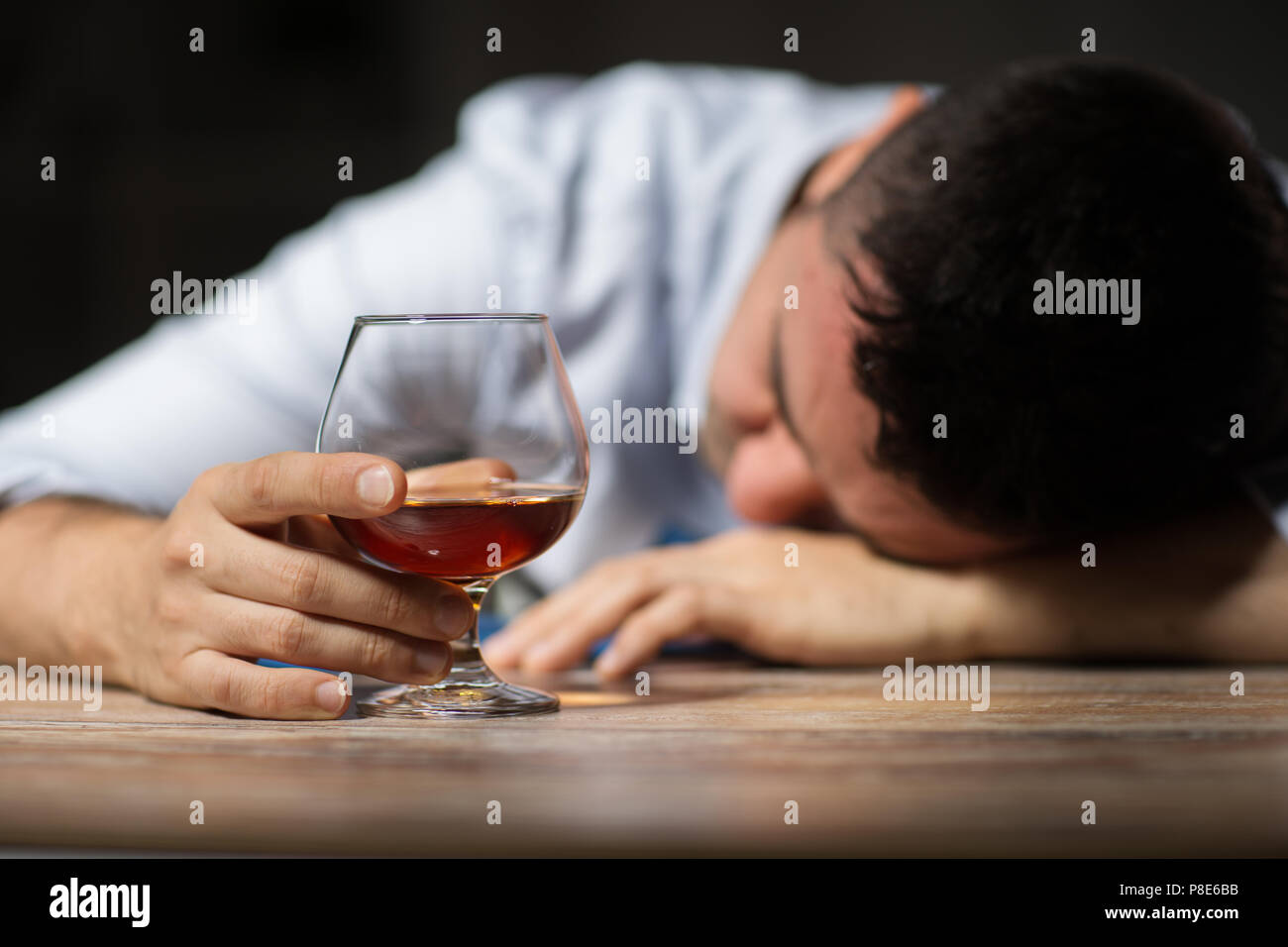 drunk man with glass of alcohol on table at night Stock Photo