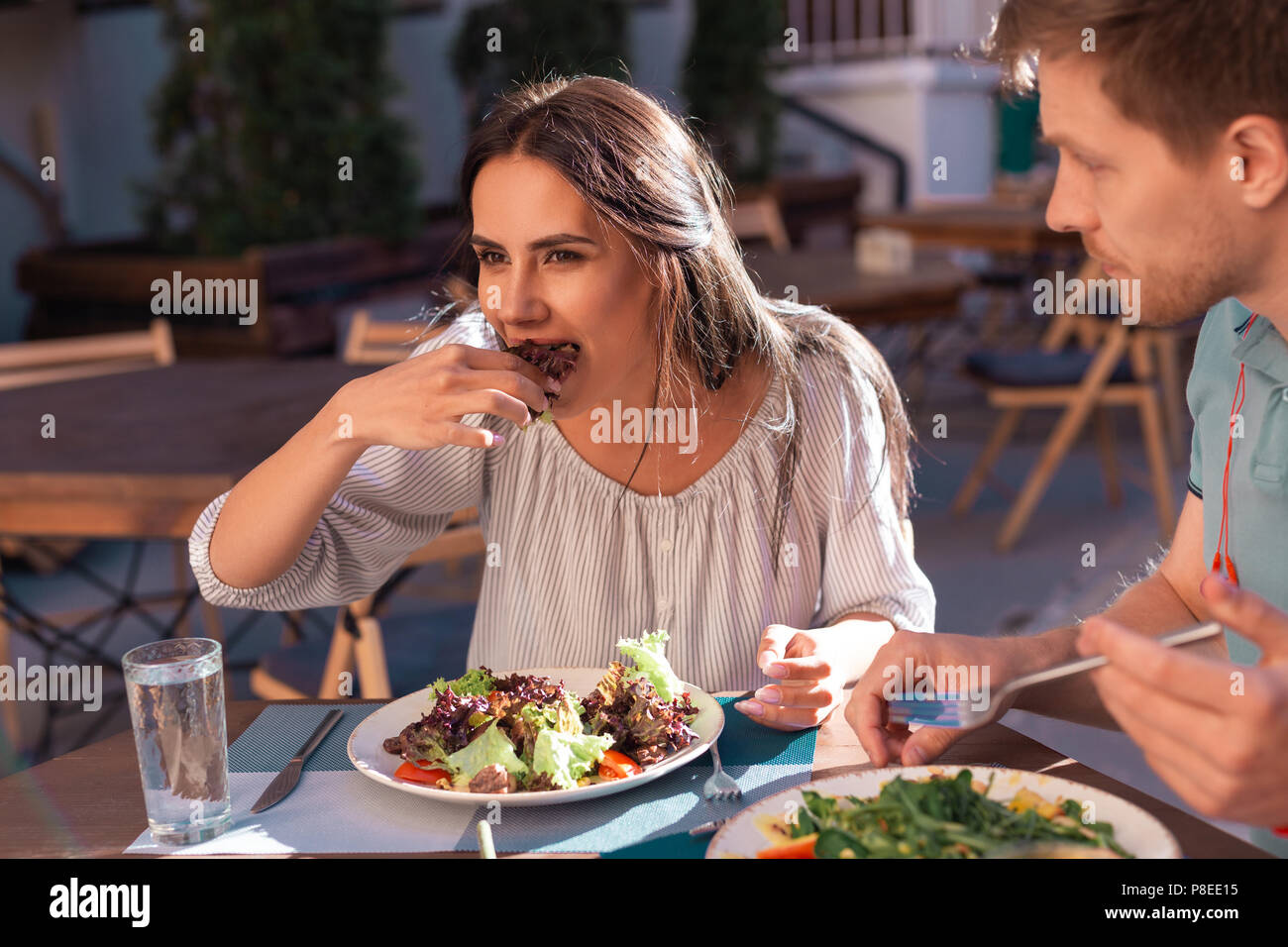 Sun tanned young woman enjoying eating salad Stock Photo
