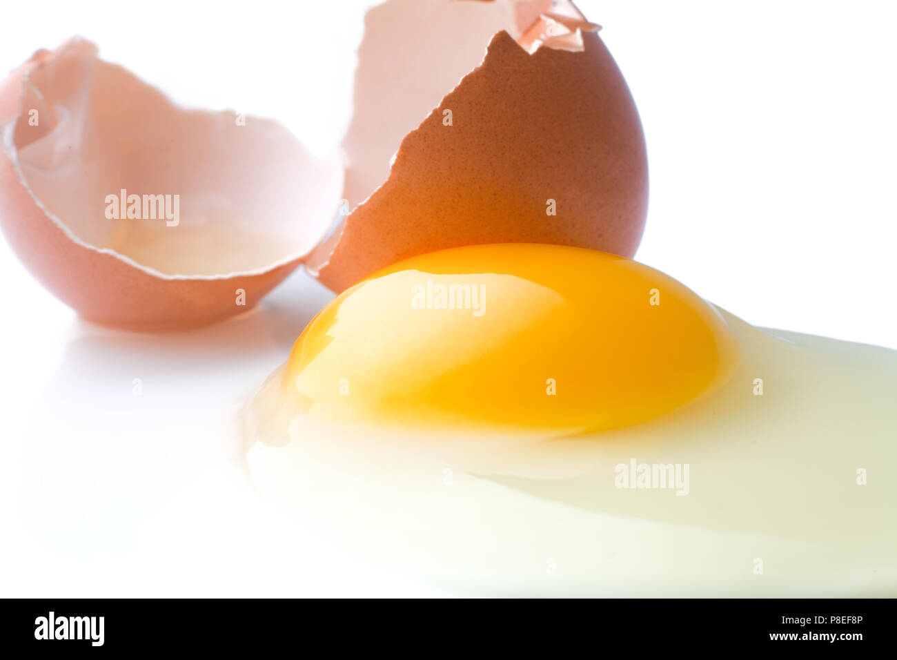 A broken chicken egg lies on a white background with a shell, yo Stock Photo