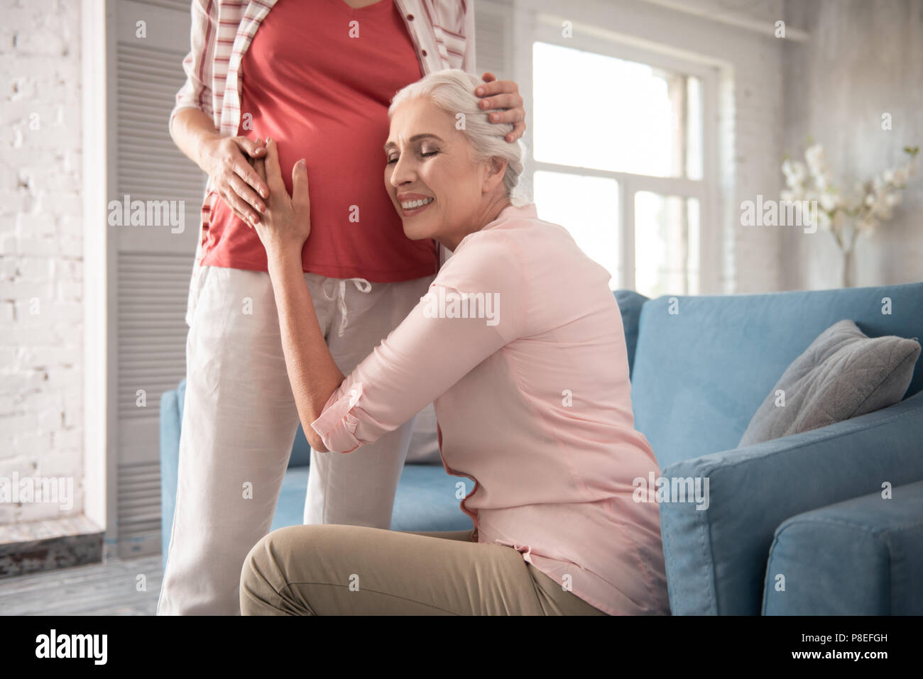 Mother of young expecting woman sitting on comfortable sofa Stock Photo