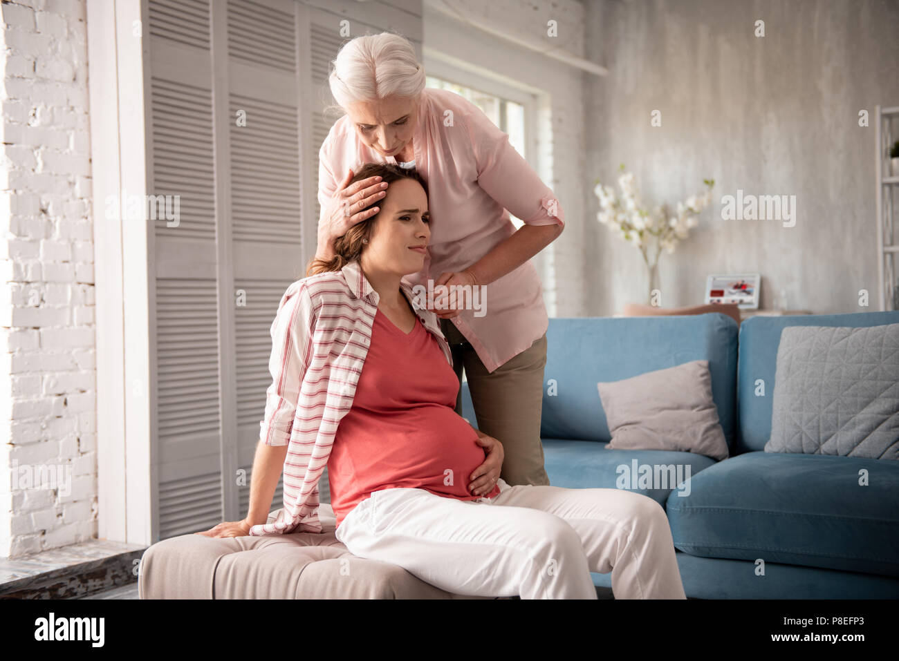 Caring mother feeling worried while pregnant daughter feeling dizzy