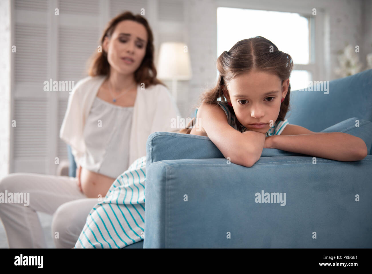 Dark-eyed little girl feeling broken after news about second child Stock Photo