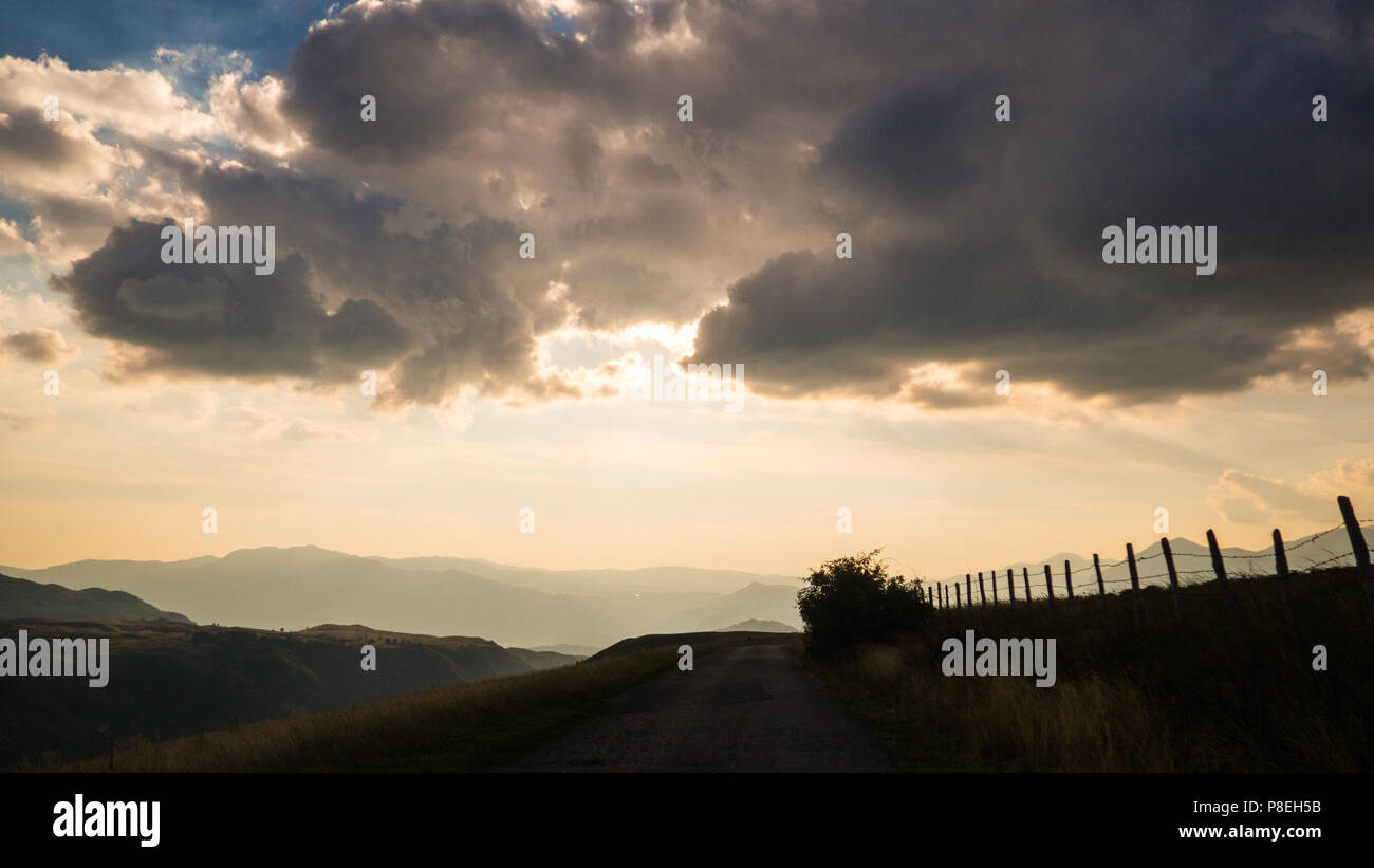 Movement on the road in the evening in cloudy day on countryside, view from inside, mountains in the background Stock Photo