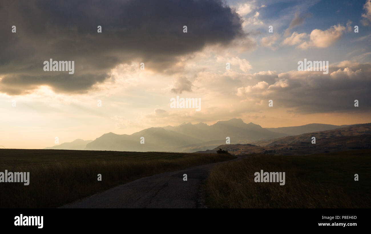 Movement on the road in the evening in cloudy day on countryside, view from inside, mountains in the background Stock Photo