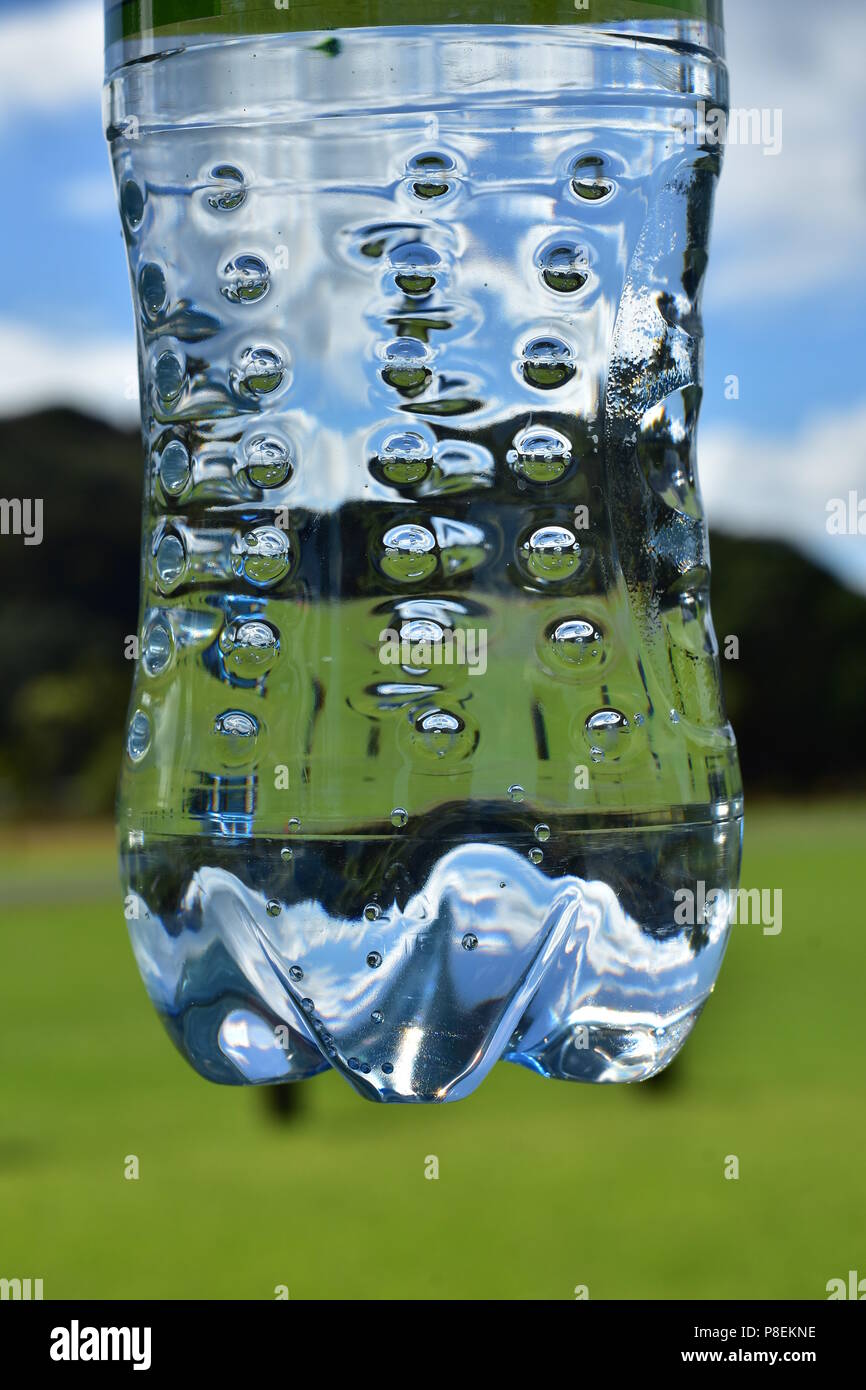 Clear plastic water bottle detail with tiny bubbles and green lawn in