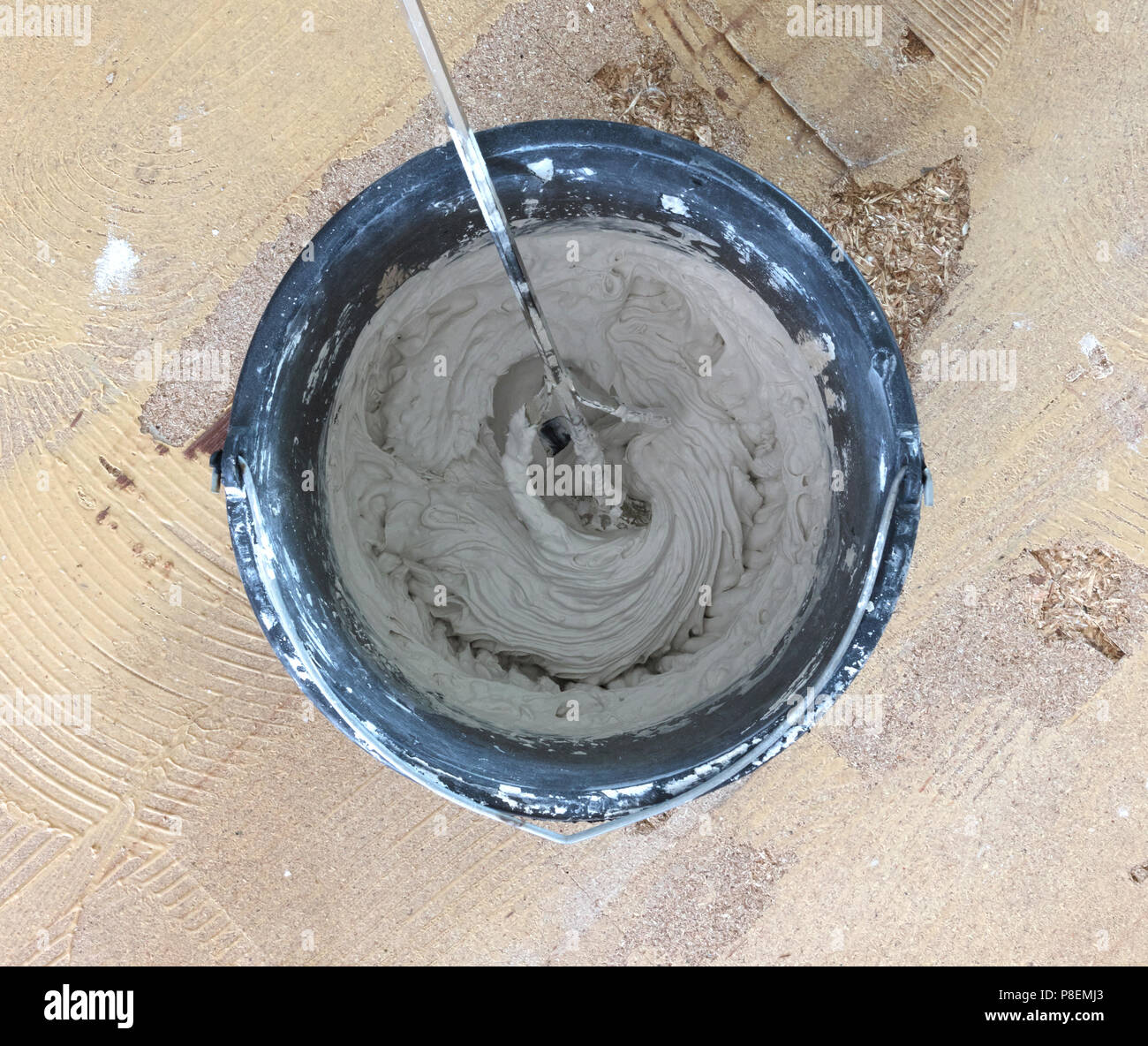 Man is holding drill mixer in his hands. Man is mixing grey concrete