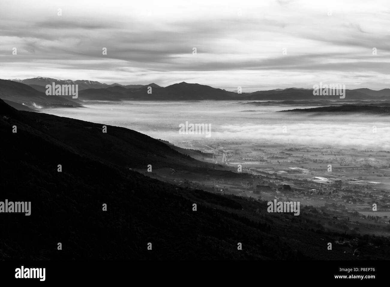 Beautiful aerial view of Umbria valley in a winter morning, with fog covering trees, houses and streets Stock Photo