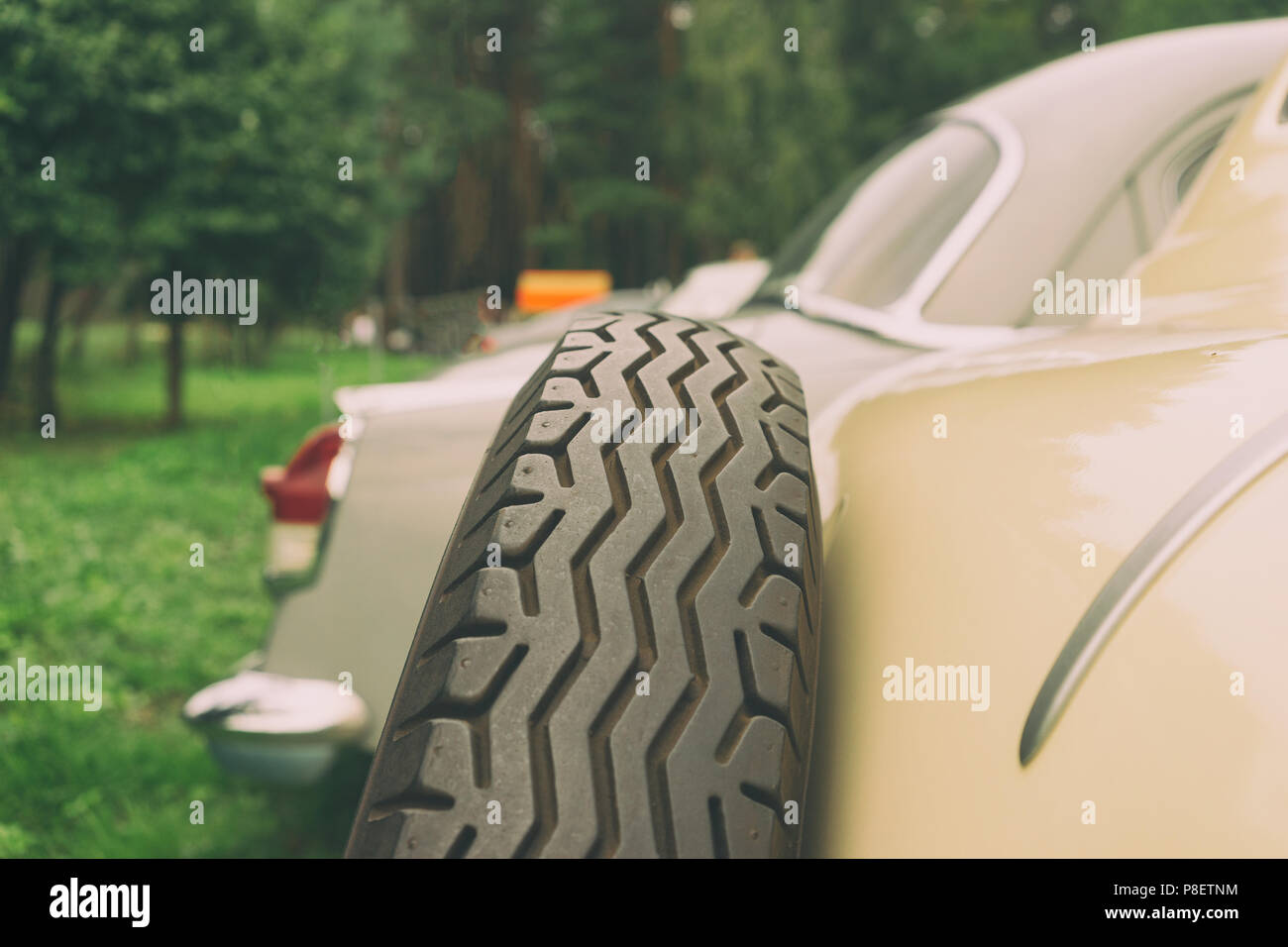 A wheel with a zigzag protector on the trunk of a vintage car in a