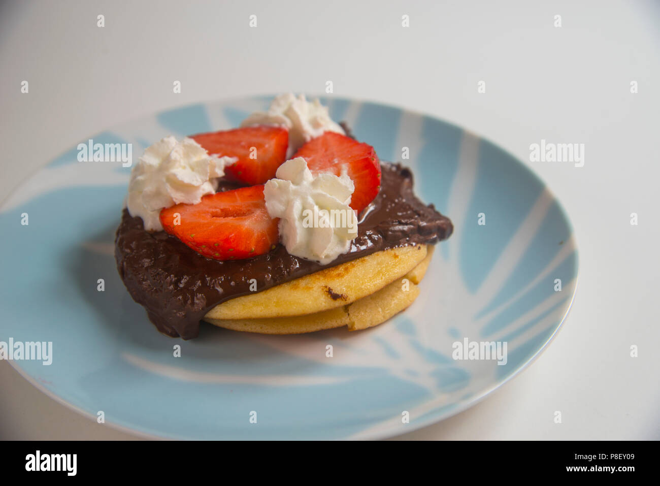 Pancakes with chocolate, strawberries and cream. Stock Photo