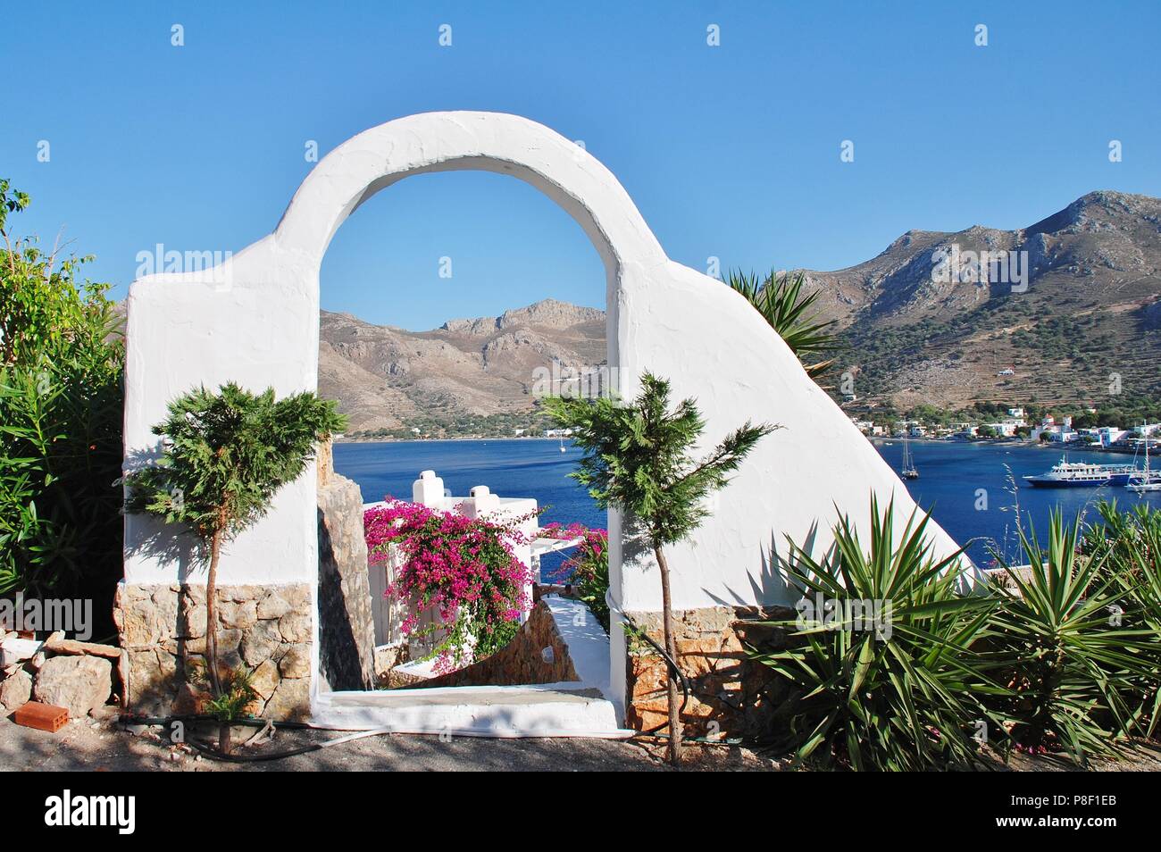 A white archway frames Livadia harbour on the Greek island of Tilos on June 12, 2018. Stock Photo