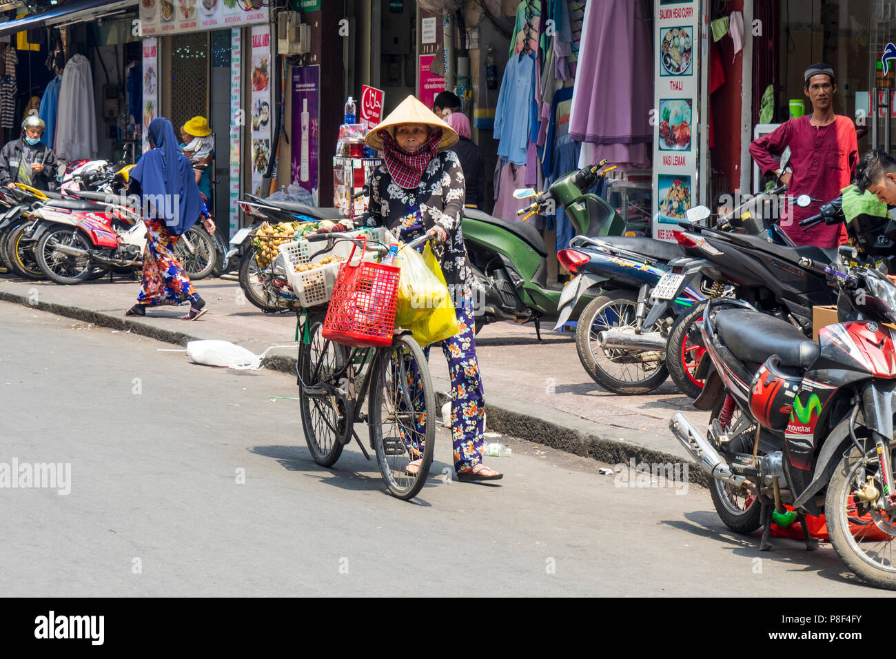Daily life, a female street vendor selling fruit from her bicycle on the street in Ho Chi Minh City, Vietnam. Stock Photo