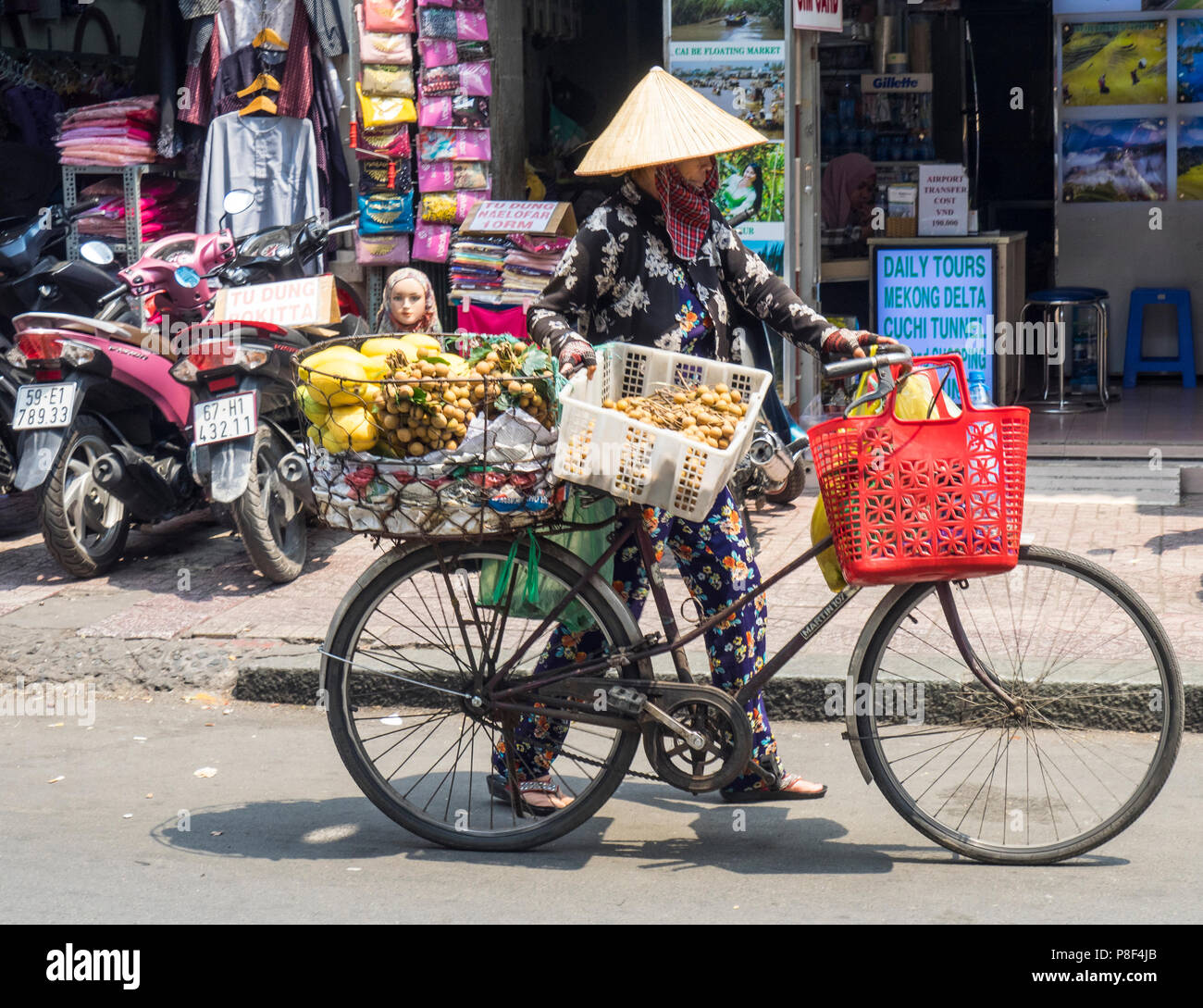Daily life, a female street vendor selling fruit from her bicycle on the street in Ho Chi Minh City, Vietnam. Stock Photo