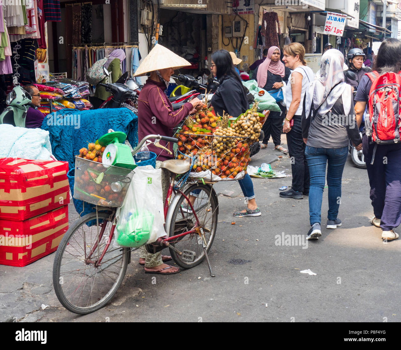Daily life, a female street vendor selling fruit from her bicycle on the street in Ho Chi Minh City, Vietnam. Stock Photo