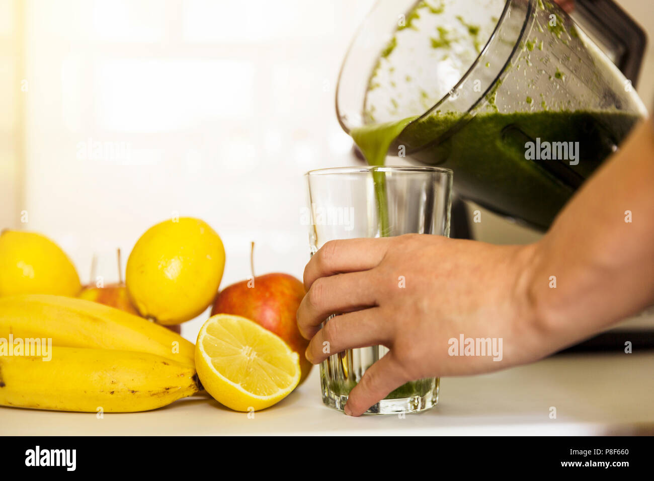 Woman blending spinach, bananas, lemon and apples to make a healthy green smoothie. Healthy