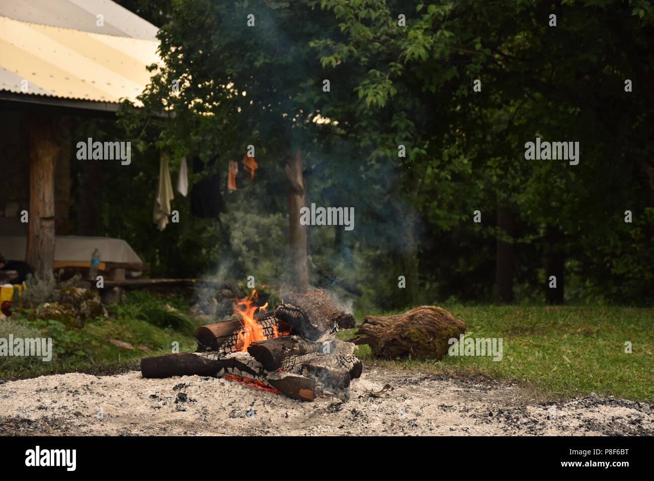 Cabin in the woods with campfire in front of it Stock Photo