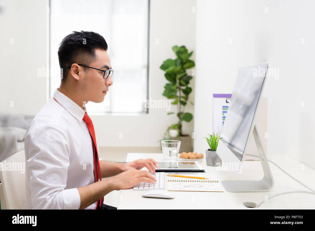 Profile view of a handsome young man doing some meditation exercises while working at the office Stock Photo