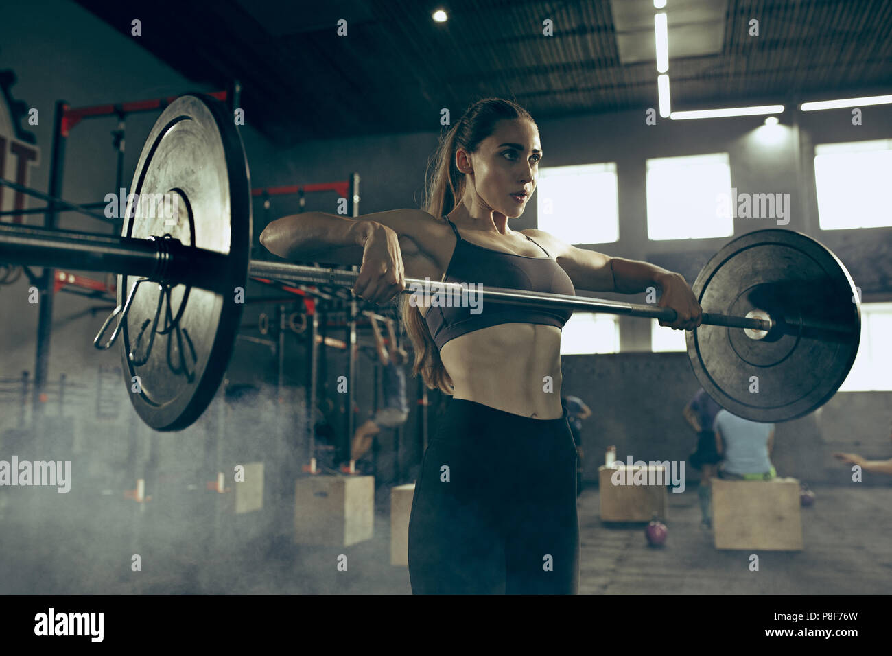 Fit young woman lifting barbells working out in a gym Stock Photo - Alamy