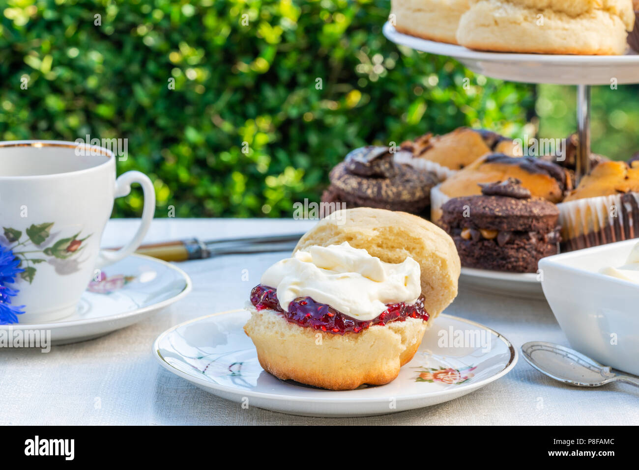 Afternoon tea with cakes and traditional English scones with strawberry jam  and clotted cream set up on a table in the garden. Outdoor dining Stock  Photo - Alamy