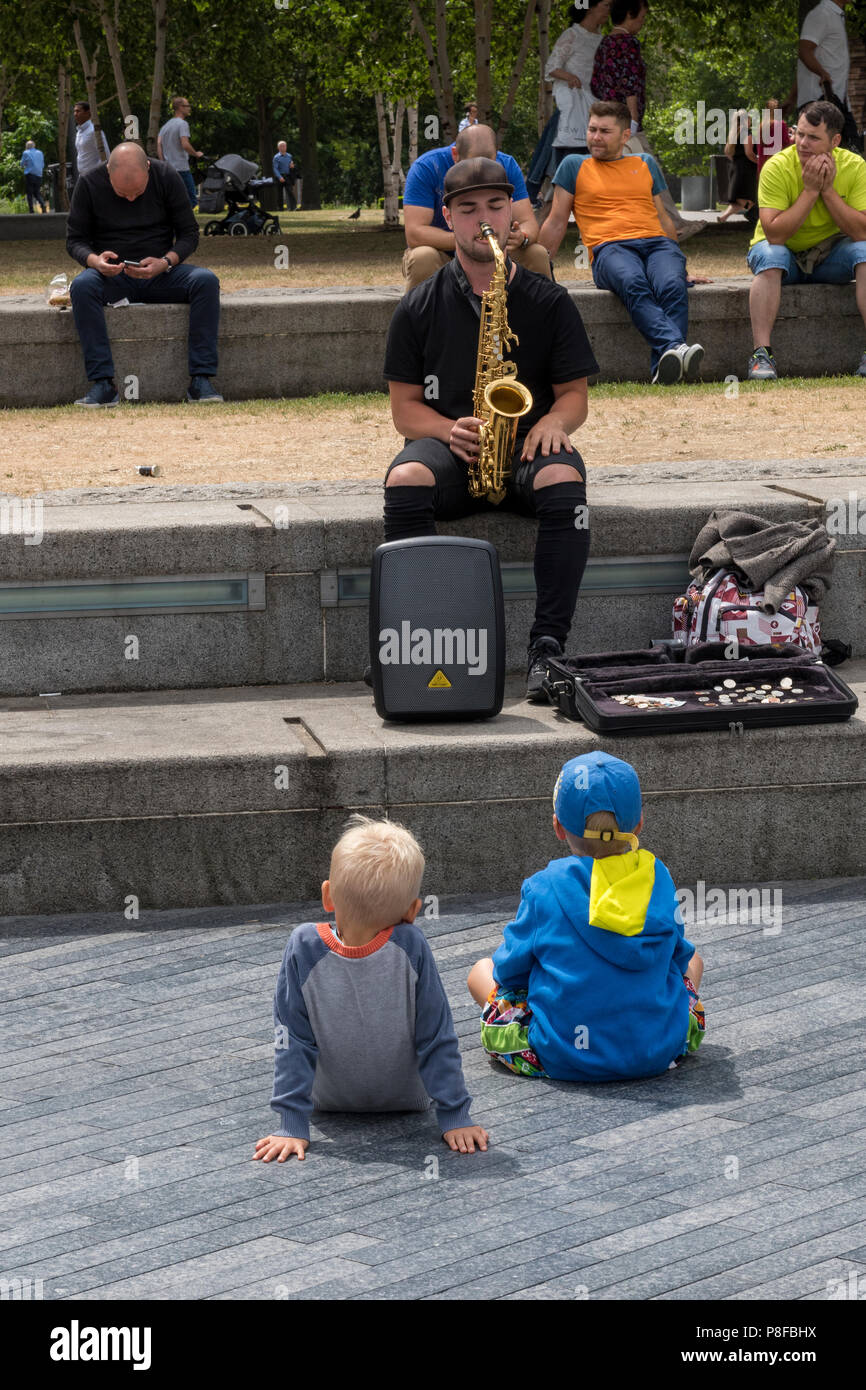 two small boys watching a street entertainer or musician, ,ore london place, london, england, uk Stock Photo
