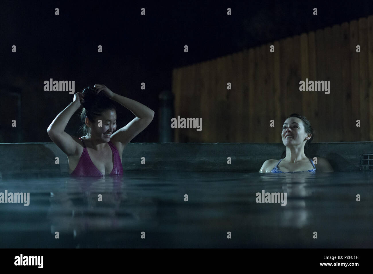 Two women in a swimming pool at night Stock Photo