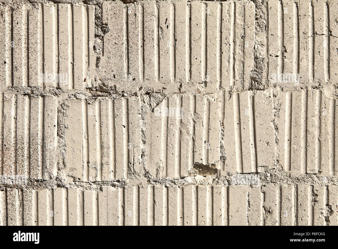 Old damaged brickwork from corrugated concrete blocks, abstract texture for backdrop. Stock Photo