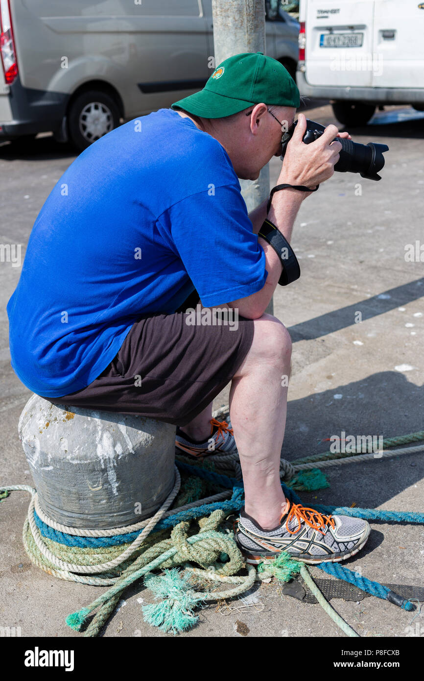 Tall older man in T shirt and shorts taking photographs Stock Photo