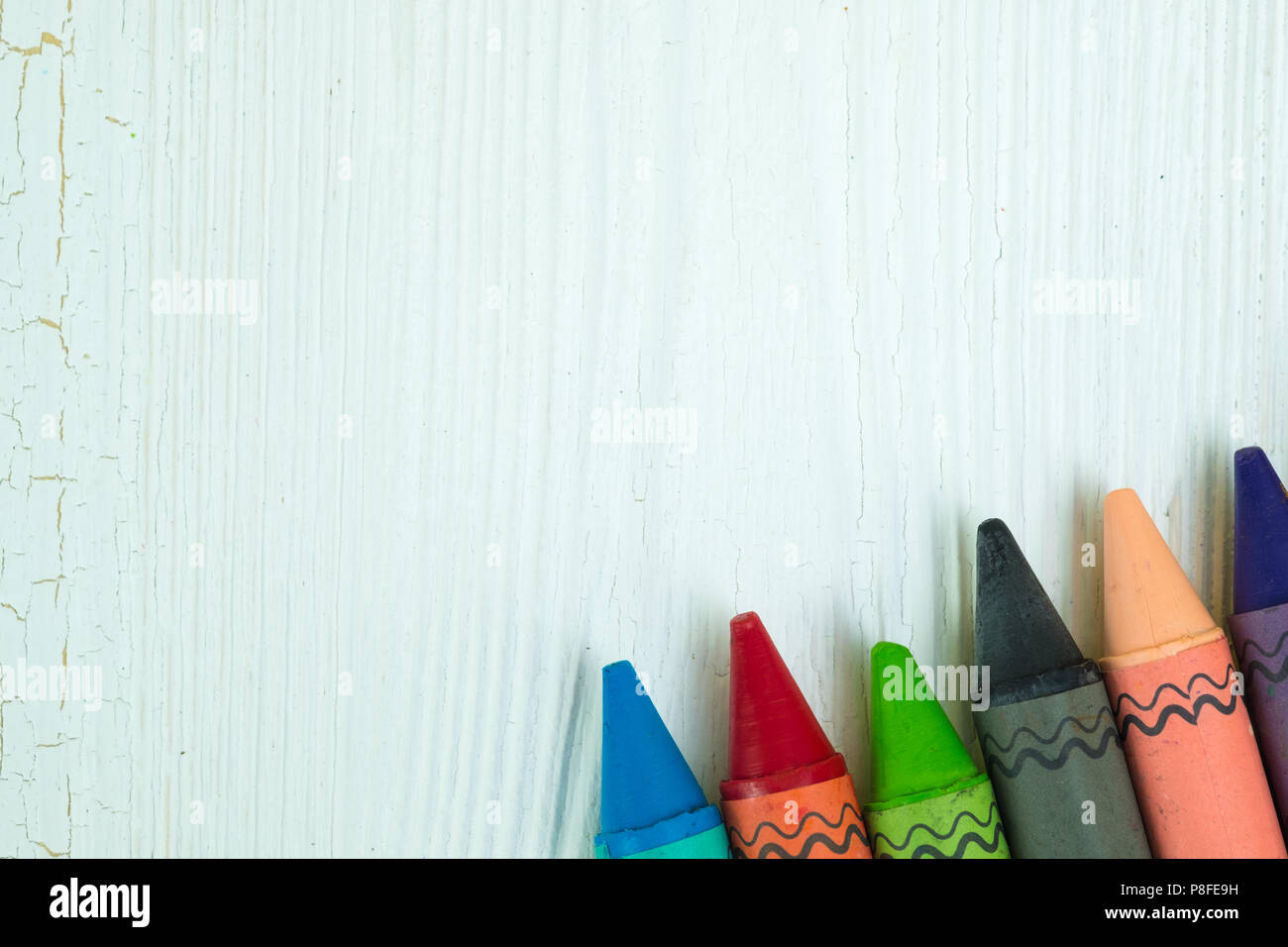 Colourful wax crayons pencils on white wood table with copy space for ...