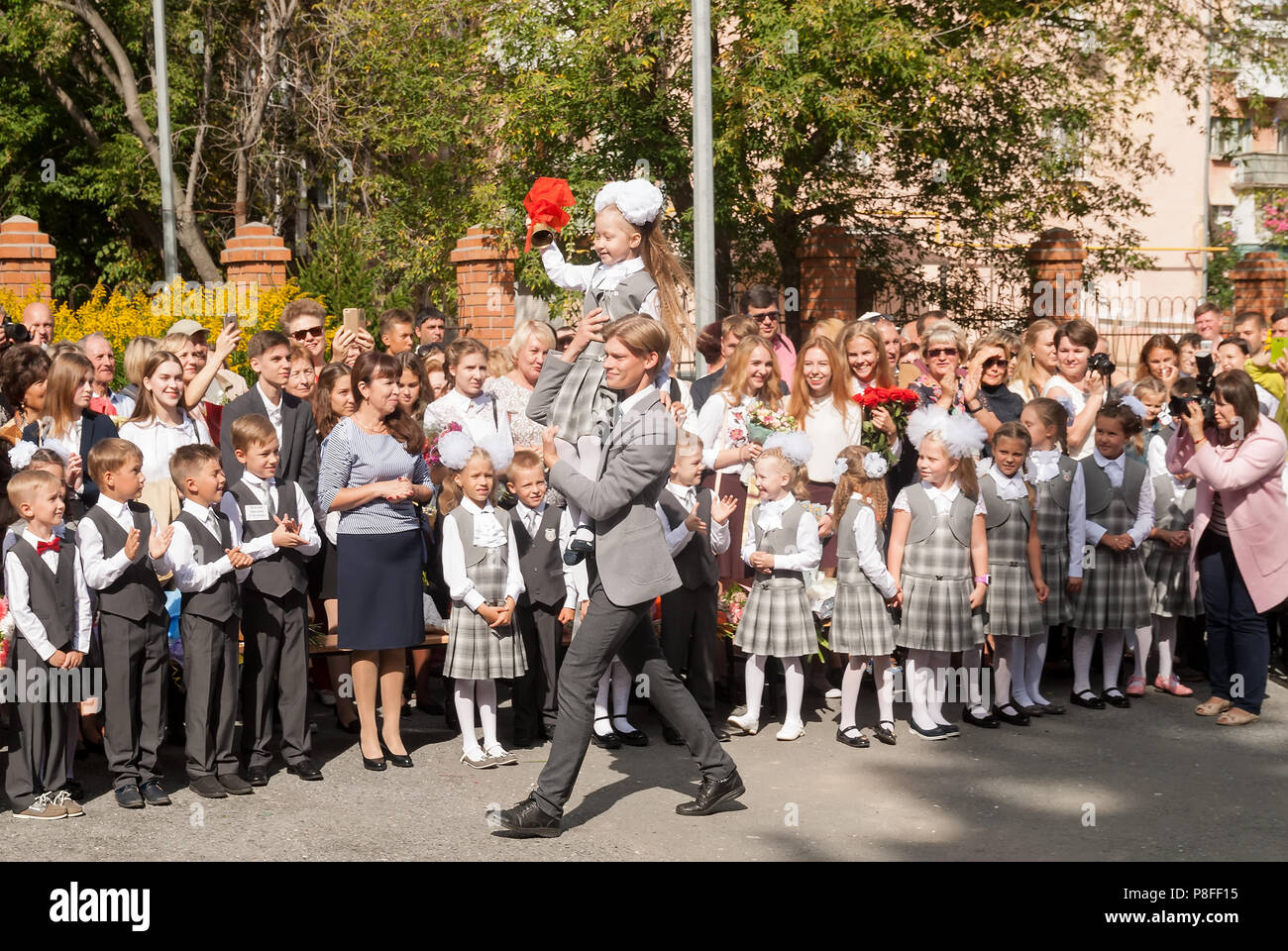 Girl ringing bell for first-graders - first bell Stock Photo