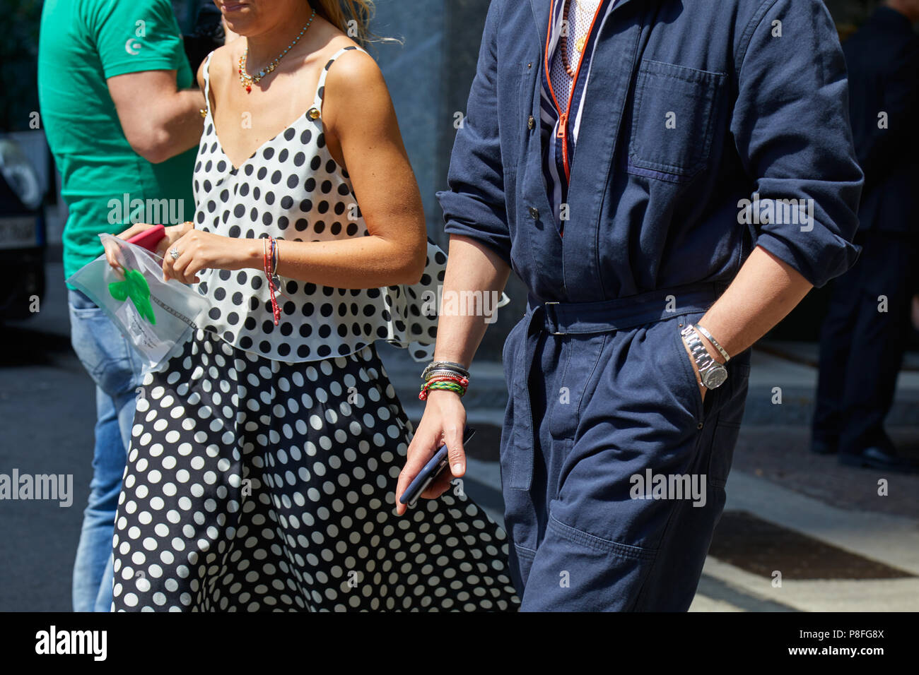 MILAN - JUNE 16: Man with blue overalls and woman with black and white polka dot shirt and skirt before Marni fashion show, Milan Fashion Week street  Stock Photo