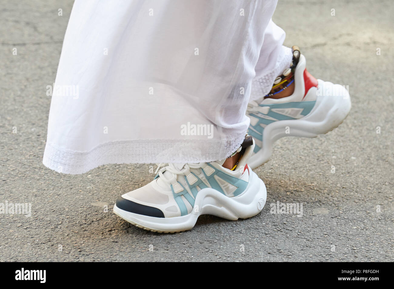 MILAN - JUNE 16: Woman with white and blue Louis Vuitton sneakers walking before Marni fashion ...