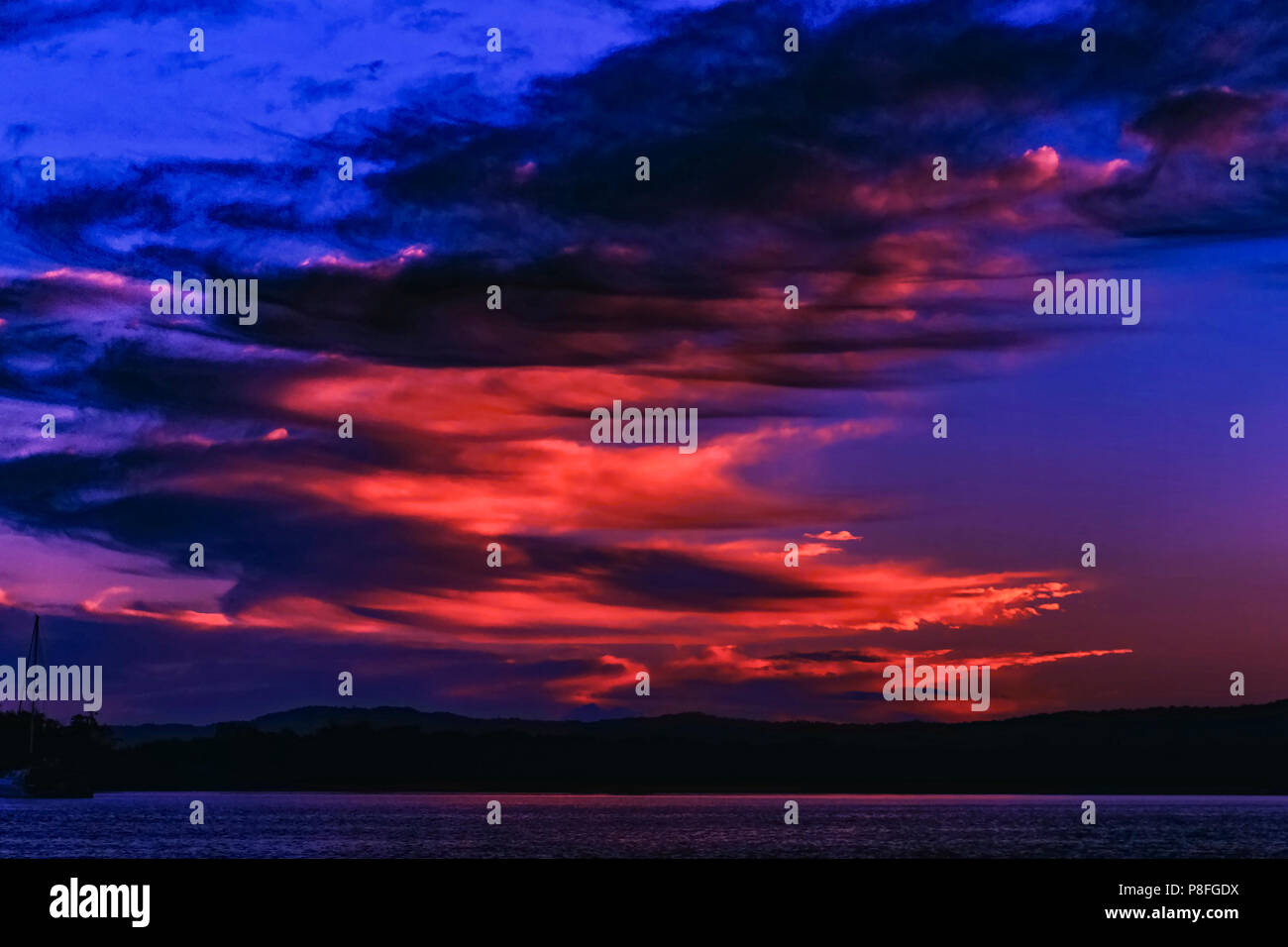 A striking inspirational crimson and cobalt blue coloured cloudy coastal sunrise. Queensland, Australia. Stock Photo