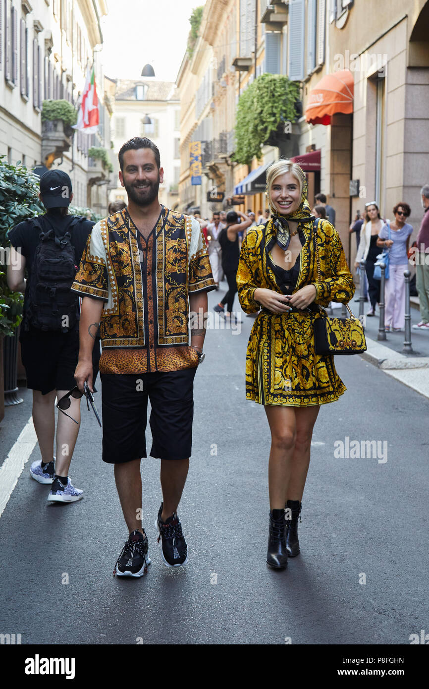 MILAN - JUNE 16: Man and woman with Versace clothing with golden designs before Versace fashion show, Milan Fashion Week street style on June 16, 2018 Stock Photo