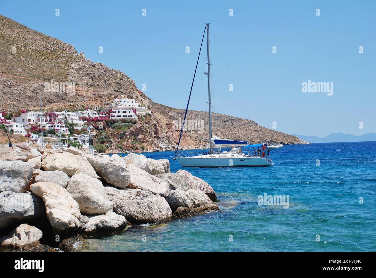 A yacht enters Livadia harbour on the Greek island of Tilos on June 12, 2018. Stock Photo