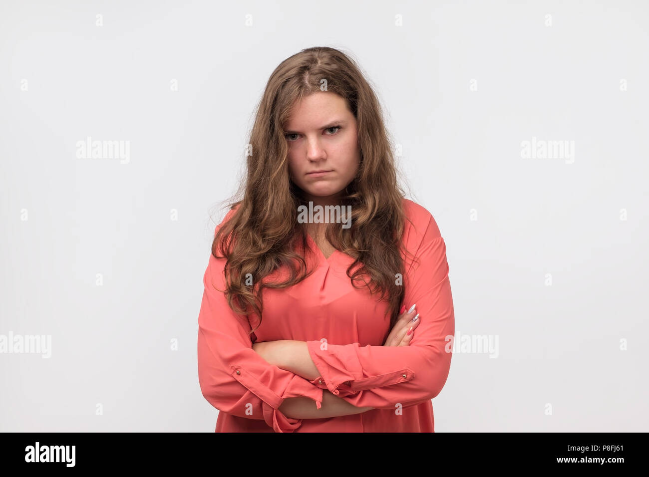 Beautiful plump girl with long hair frowning her face in displeasure. She is offended on her boyfriend. He forgot about a date. Stock Photo