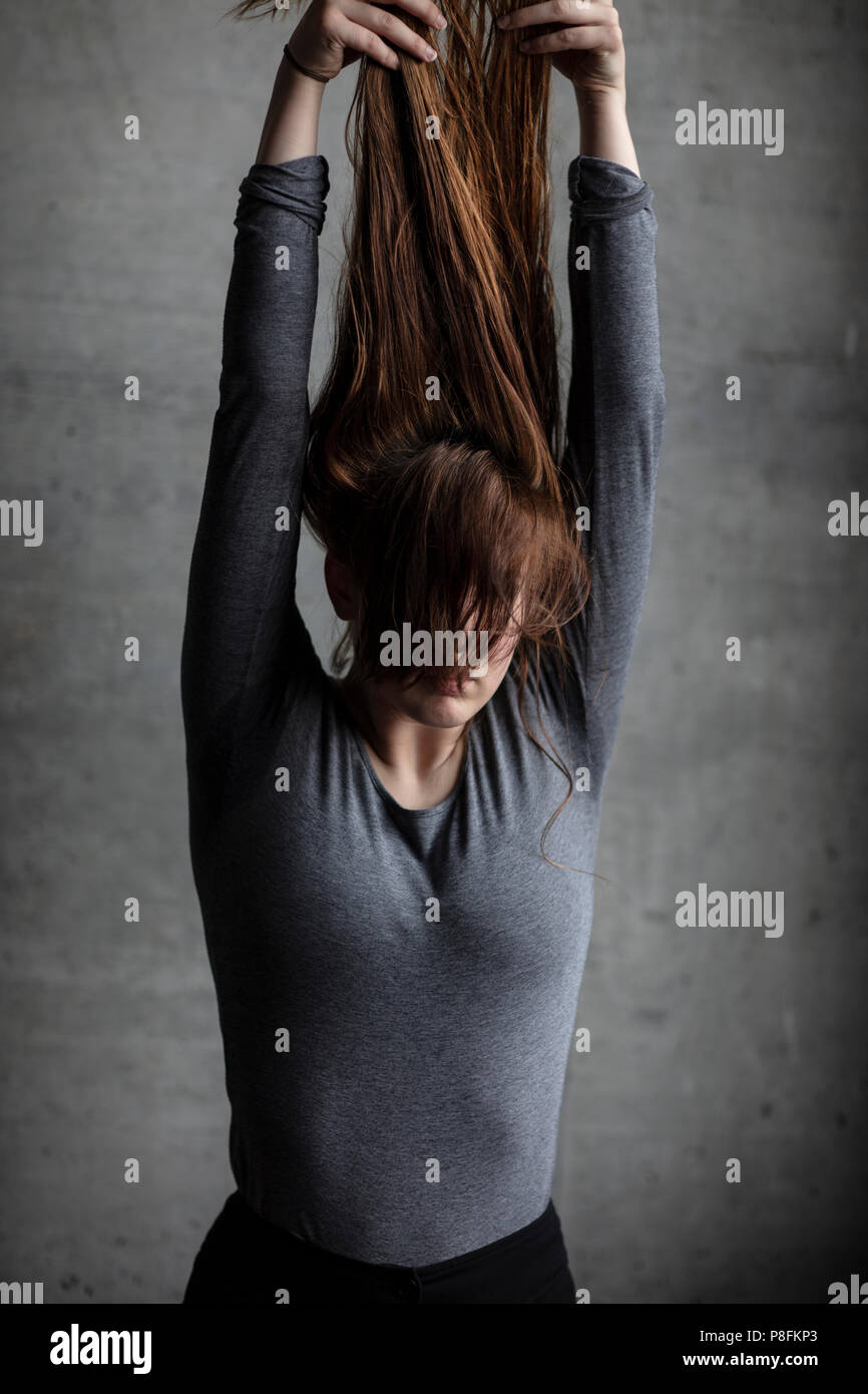Female model lifting hair above head with arms fully stretched upwards