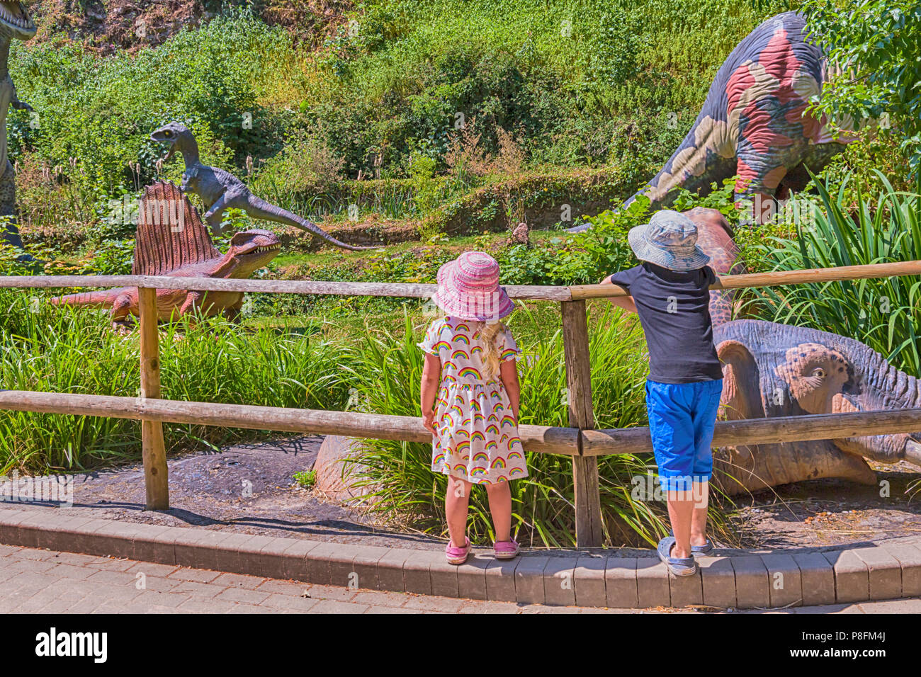 Children looking at the dinosaurs in the Prehistoric Dinosaur Valley at Wookey Hole, Wells, Somerset, UK in July Stock Photo