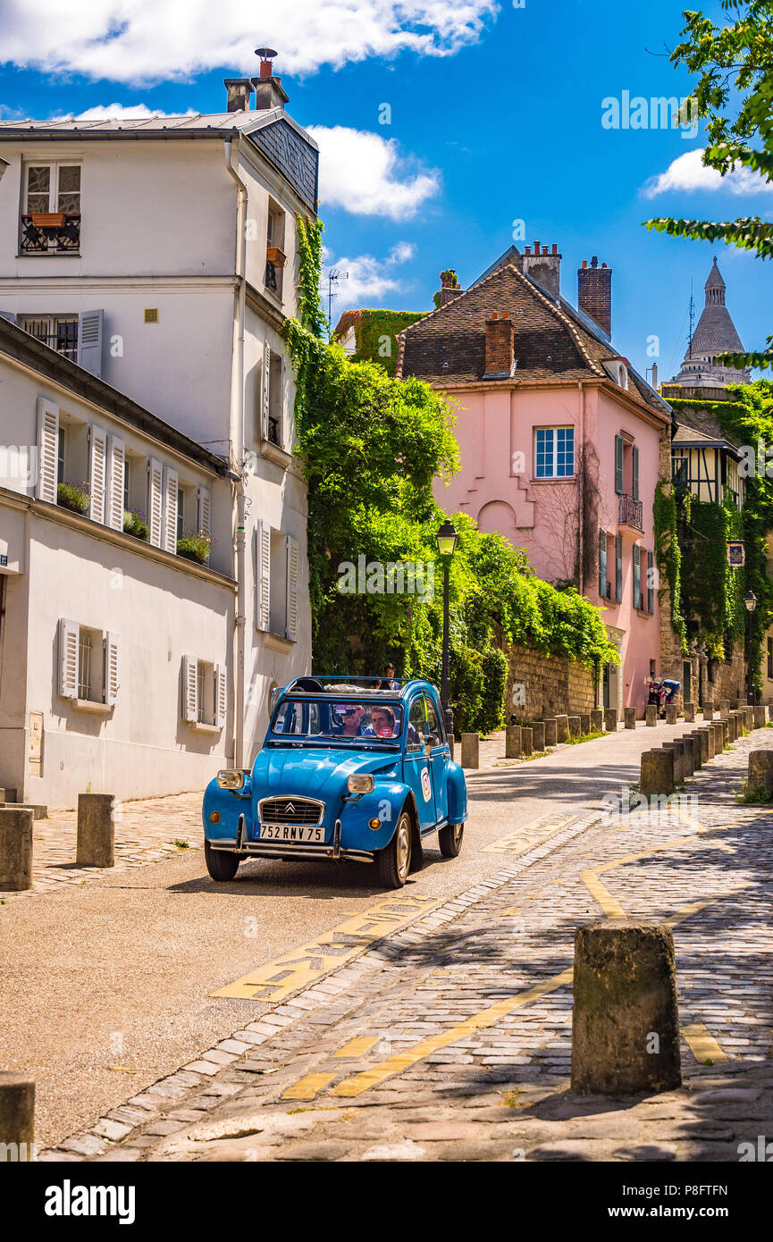 A bright blue 1940's classic car, the Citroen 2CV passed down Rue de l'Abreuvoir in Montmartre, Paris, France. Stock Photo