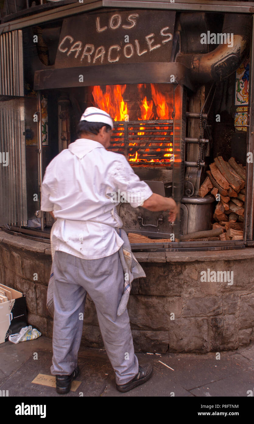 Man Cooking snails outdoors over an open fire Stock Photo