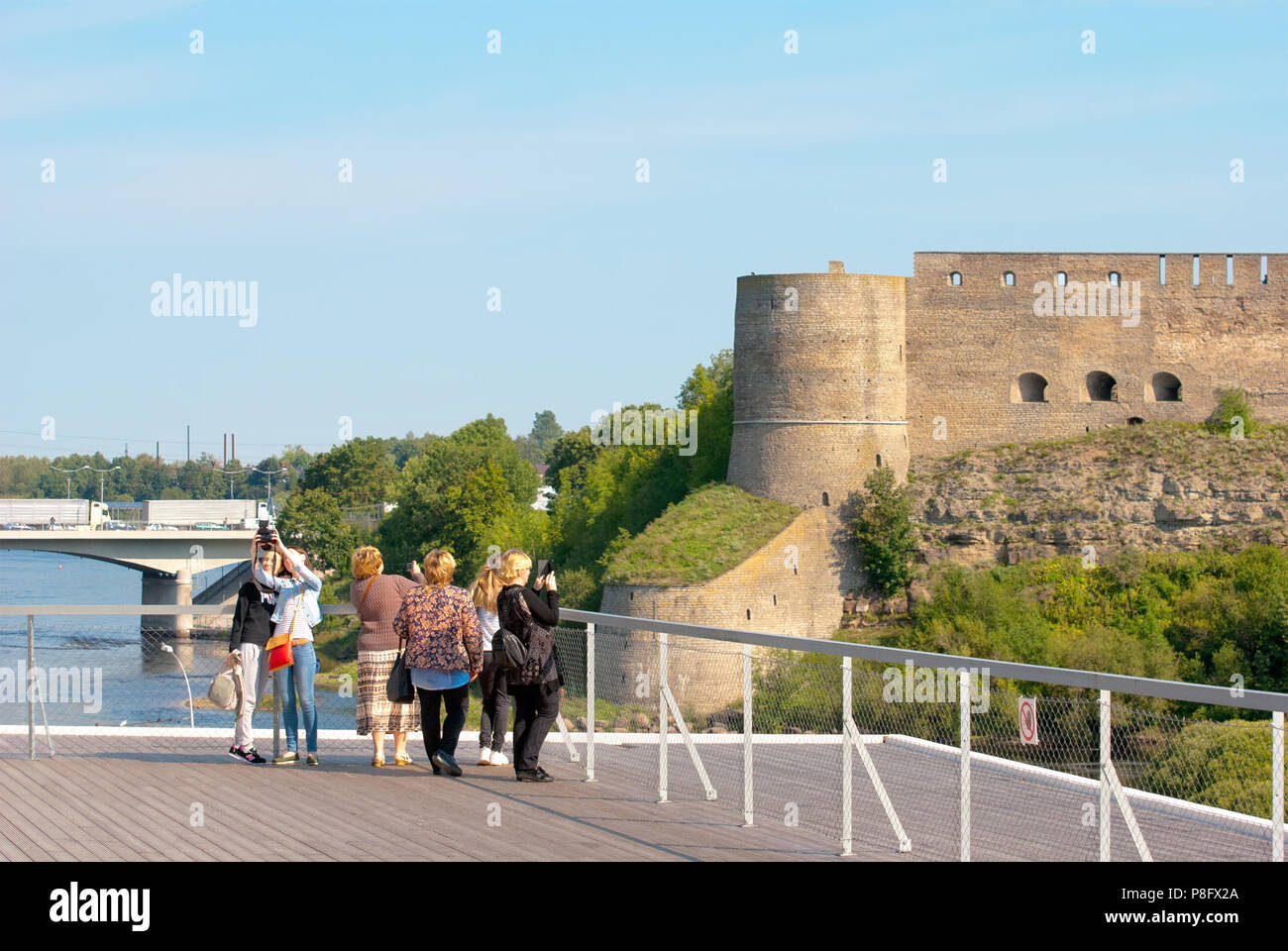 NARVA, ESTONIA - AUGUST 21, 2016: People on observation deck in Estonian Town Narva take pictures in front of the Ivangorod Fortress in Russia Stock Photo