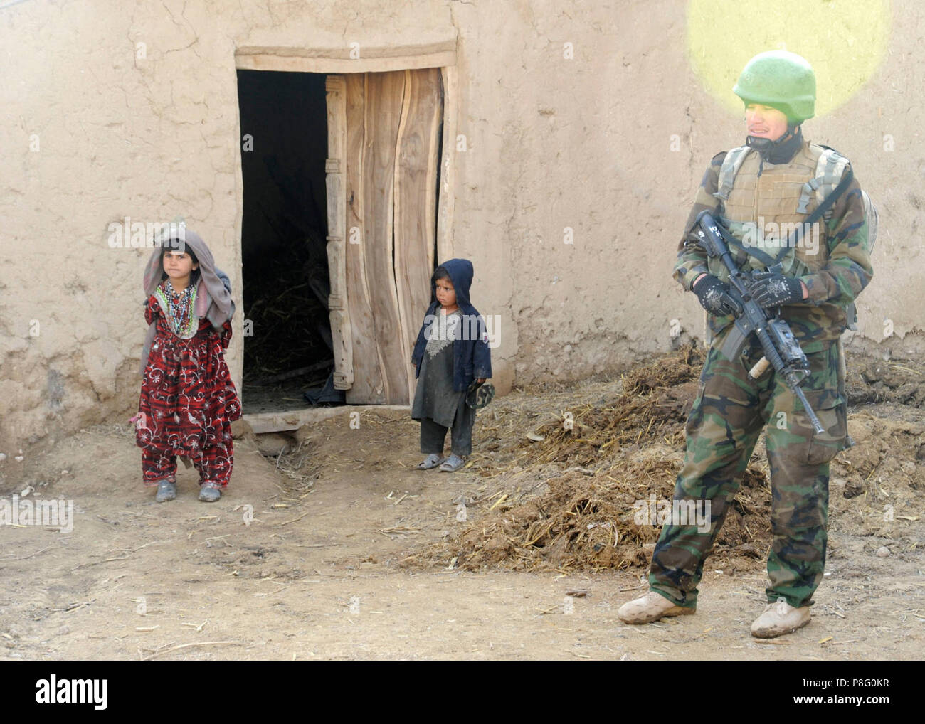 8th Commando Kandak operation . Village children emerge from their home to observe the activity of a soldier from the 8th Commando Kandak in Doan-e Ulya Village, Shahid-e Hasas district, Uruzgan province, Afghanistan, Feb. 6. The 8th Commando Kandak partners with coalition special operations forces to conduct operations throughout Uruzgan and Zabul provinces. Stock Photo