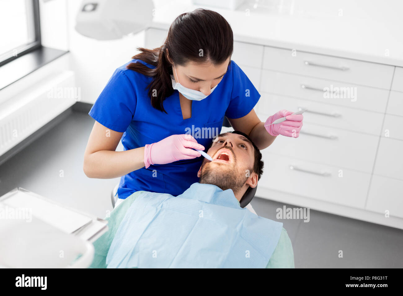 female dentist checking up male patient teeth Stock Photo - Alamy