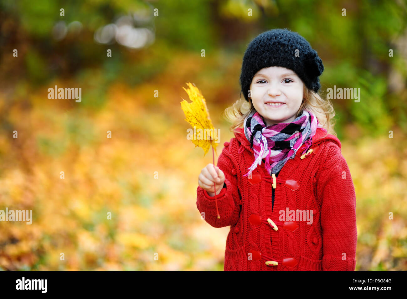 Little girl in a red coat at autumn holding leaf Stock Photo - Alamy